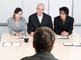 Panel interview in a bank, with three interviewers, two male and one female, and a young job applicant sitting in front of them